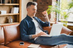 a person sitting on a couch and using a laptop